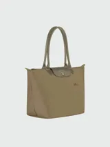 Bolso tipo tote Longchamp modelo Le Pliage Green en tamaño grande, color verde oliva. Presenta diseño minimalista con solapa y asas de cuero en tono a juego, cierre superior con cremallera y el icónico logo del caballo bordado en el frente.