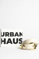 Cinturón color crema con hebilla dorada.