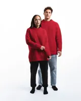 Sweater unisex de lana merino fina color rojo, con cuello redondo y corte relajado. Presenta un motivo inspirado en la técnica de zurcido visible.