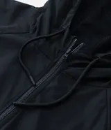 Campera rompeviento deportiva de color negro, con cierre frontal de cremallera, capucha ajustable con cordón, bolsillos laterales y ruedo elástico. Presenta recortes delanteros y diseño de manga larga.
