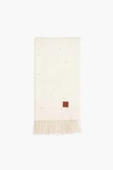 Pashmina de tejido de punto color blanco, decorada con pequeñas perlas dispersas por toda la superficie. Presenta flecos en los extremos y una etiqueta de cuero sintético con logo en una esquina.