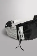 Riñonera deportiva técnica de Zara Athleticz en combinación de colores blanco y negro, con dos compartimentos principales, bolsillos laterales y sistema de sujeción con cordón elástico.