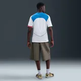 Camiseta deportiva Nike Total 90 Energy de manga corta, color blanco con detalles en dorado, verde, azul y rojo. Presenta un diseño de paneles curvos, cuello en V tricolor y el gráfico distintivo '90' en el centro del pecho.