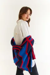 Camisa oversize de algodón color blanco, con cuello clásico, cierre frontal de botones y detalle de costuras decorativas en zigzag a lo largo de la botonera. Presenta mangas largas con puños estructurados y un diseño versátil que permite ajustar la silueta.