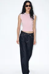 Chaleco de punto color blanco, estilo polo, sin mangas (manga sisa) y cuello solapa. La parte inferior termina en rib.