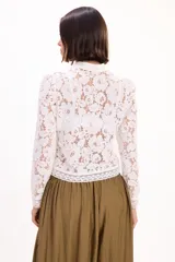 Blusa blanca de encaje con cuello mao, manga larga y cierre frontal con presillas y botones de tela.