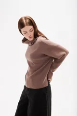 Polera de punto color camel, con cuello alto holgado y mangas largas de diseño amplio.