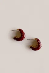 Aros abridores tipo argolla corta, enchapados en oro con esmalte rojo brillante y pequeños puntos dorados en relieve.