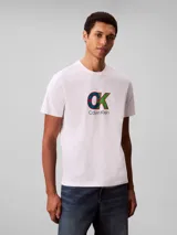Remera de cuello redondo y manga corta, confeccionada en algodón regenerativo. Presenta un estampado gráfico frontal con el monograma de la marca en colores azul, verde y rojo, acompañado por el logo de Calvin Klein debajo.