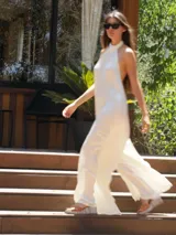 Mono largo de satén color blanco, con cuello halter y diseño amplio de pierna ancha.