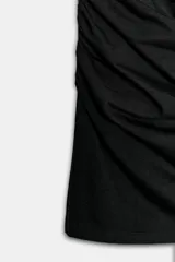 Vestido corto de algodón color negro, con cuello redondo, mangas cortas amplias y detalle de frunces elásticos laterales.