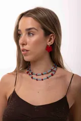 Collar de doble vuelta compuesto por bastones de vidrio celestes y pequeñas piedras irregulares de color rojo. Cuenta con herrajes de acero quirúrgico y diseño ajustable.