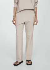 Pantalón de tiro alto con diseño jogger, confeccionado en tejido liso con cintura elástica fruncida y bolsillos laterales.