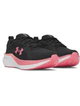 Championes de running Under Armour modelo Assert 11, color negro con detalles en rosado y suela blanca. Presentan parte superior de malla transpirable con revestimientos de cuero, amortiguación Charged+ en la mediasuela y suela de goma resistente.