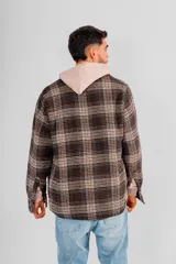 Sobrecamisa de hombre con cuello camisero, botones frontales y bolsillos de parche en el pecho. Presenta un estampado a cuadros en tonos marrones, negros y beige.
