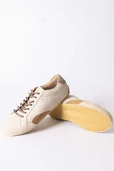 Championes urbanos de gamuza color marrón, con suela de goma en tono crema y cordones jaspeados. Presenta un refuerzo en la puntera y un detalle en cuero beige en el talón.