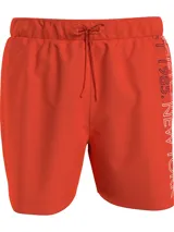 Short de baño Tommy Hilfiger color naranja, con cintura elástica ajustable mediante cordón. Presenta un diseño liso con el logo de la marca estampado verticalmente en el lateral izquierdo.