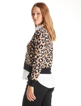 Buzo de la marca Ninety con estampado animal print en tonos beige, negro y blanco. Presenta cuello en V con solapa y botones frontales, simulando una camisa blanca debajo. Las mangas son largas y el ruedo también simula el de una camisa.