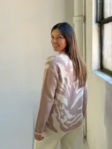 Sweater de tejido de punto con diseño abstracto en tonos beige y crema, de corte holgado, cuello redondo y manga larga.