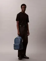 Mochila Calvin Klein de poliuretano texturizado en color azul, con compartimento principal con cierre de doble cremallera, bolsillo frontal con cierre, asa superior y tirantes ajustables. Incluye detalle de logo metálico de la marca en el frente.