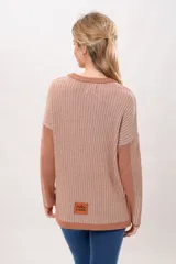 Sweater de punto color salmón con rayas verticales en relieve. Tiene cuello redondo y corte holgado.