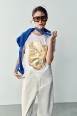 Camiseta blanca de manga corta y cuello redondo, con detalle de estampa central metalizada de efecto texturizado y diseño regular fit.