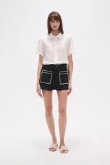 Short de jean color azul oscuro, de calce alto y ajustado al cuerpo. Presenta dos bolsillos frontales cuadrados con bordado decorativo en color blanco.