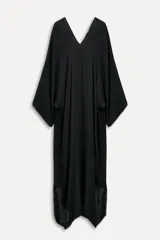 Vestido negro tipo capa confeccionado en hilatura de viscosa, con escote pico, manga corta y bajo asimétrico desflecado.