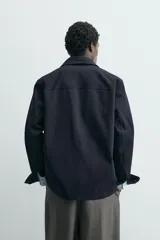 Sobrecamisa de corte relajado confeccionada en tejido de algodón con elasticidad. Presenta cuello solapa, cierre frontal con botones, manga larga con puños abotonados y dos bolsillos plastrón en el pecho.