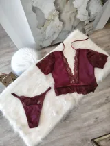 Conjunto de lencería compuesto por un top de encaje y satén con escote profundo y una tanga regulable a juego. El top presenta mangas cortas de encaje, detalles de puntilla en el escote y bajo, y cierre posterior. La tanga cuenta con detalles de encaje y forro de algodón.