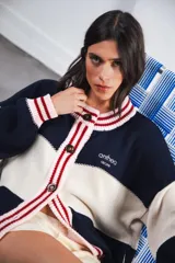 Cardigan oversized de punto grueso, color azul marino y blanco con franjas rojas y rosadas en el cuello, puños y solapa. Tiene botones grandes marrones y el logo de Anthea bordado en el pecho.