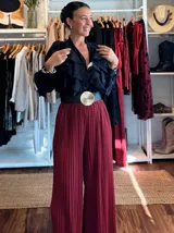 Pantalón de corte palazzo en tejido plisado con acabado brillante tipo lurex, color rojo intenso. Presenta una cintura elástica cómoda y una caída fluida y amplia.