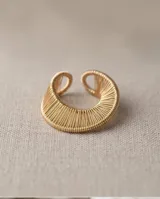 Anillo de bronce con acabado dorado, diseño entrelazado de líneas finas y textura acanalada.