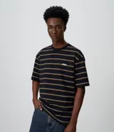 Remera negra de corte relaxed, confeccionada en algodón con diseño de rayas finas horizontales en blanco y mostaza. Cuenta con cuello redondo, mangas cortas y un pequeño bordado ovalado en el pecho.