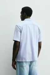 Camisa de manga corta color verde grisáceo, de corte regular fit, confeccionada en tejido suave y elástico con cierre de botonadura frontal.