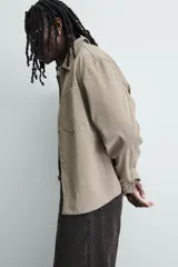 Sobrecamisa boxy fit de hombre confeccionada en tejido efecto ante color beige, con cuello solapa, manga larga con puño abotonado, bolsillo de parche en el pecho y cierre frontal con botones a presión ocultos.