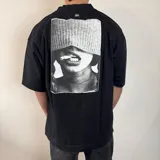 Remera de corte oversize confeccionada en algodón pesado, color negro, con estampa fotográfica en blanco y negro aplicada en la espalda.