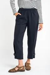 Pantalón ancho azul marino con cintura elástica, bolsillos laterales y detalle de botones en el tobillo.