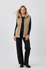 Chaleco de corderito en color beige, con cierre frontal de botones a presión y cuello alto.