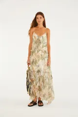Vestido largo de poliéster con forro de viscosa, de corte amplio y silueta fluida en capas, con estampado tropical de palmeras en tonos verdes y tostados sobre fondo beige, escote en V y tirantes finos.