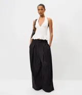 Pantalón de sastrería negro de cintura alta, con pinzas frontales y diseño fluido de perneras anchas.