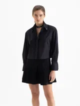 Camisa de poplín de algodón, color negro, de corte cómodo y largo que cubre hasta debajo de la cintura. Presenta botones ocultos en cartera y puños, y punteras de níquel en el cuello.