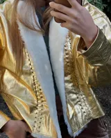 Campera oversize de cuero tostado con solapas y forro interno de corderito sintético azul marino, mangas anchas y detalles de costuras trenzadas.