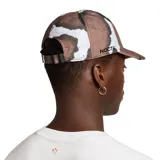 Gorro de visera Nike Nocta color marrón con estampado abstracto en tonos marrones y blancos. Logotipo de Nocta bordado en el lateral.