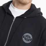 Campera con cierre frontal y capucha, color beige, con logo circular de la marca Reef estampado en el pecho y bolsillos tipo canguro.