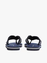 Ojotas Tommy Hilfiger azul marino con tiras de tela trenzada con rayas blancas y suela plana.