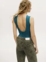 Body sin mangas de tejido acanalado con acabado brillante, cuello redondo a la base y espalda baja descubierta. Presenta un corte entallado al cuerpo con cierre de botones a presión en la parte inferior.