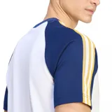 Remera deportiva de manga corta Adidas Originals del Real Madrid, de color blanco con mangas azules y detalles en amarillo. Incorpora el logo del trébol y el escudo del club bordados en el pecho.