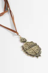 Collar de cordón marrón con dije de escudo plateado con detalles grabados y sol en la parte superior.