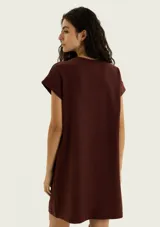 Vestido corto marrón de corte recto y holgado, con mangas cortas con vuelta, cuello redondo y un bolsillo aplicado en el pecho.